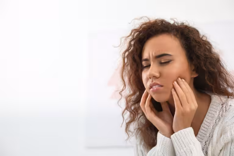 Woman experiencing jaw pain caused by stress-related teeth grinding