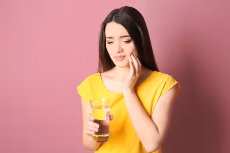 Patient experiencing tooth sensitivity while drinking a cold beverage
